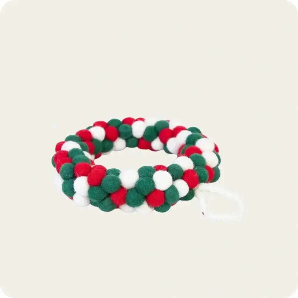 Handcrafted Christmas decor made from felt balls in festive red, green, and white colors, arranged in a decorative ring.