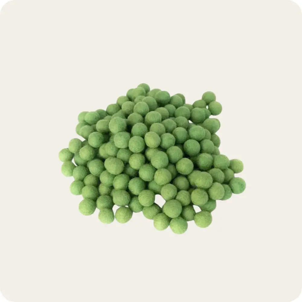 A pile of green felt balls arranged on a light background, showcasing their round shape and soft texture, ideal for crafting and decoration purposes.